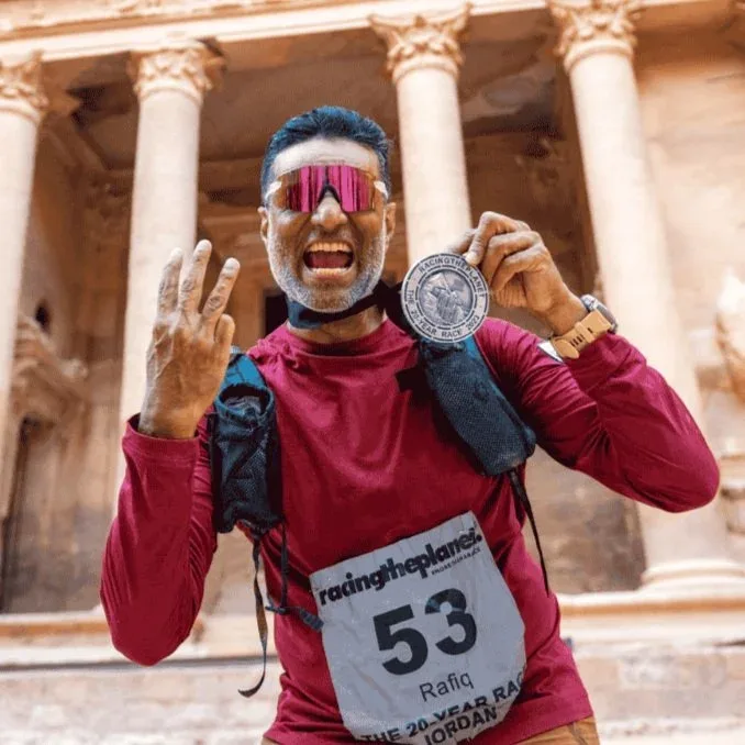 Rafiq Karovaliya holding his finisher's medal at Racing the Planet's race in Jordan